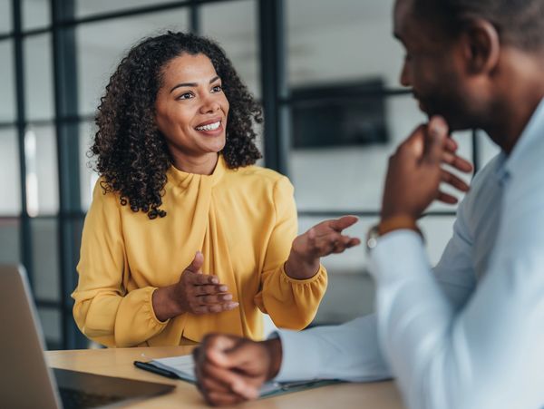 Two professionals engaged in a friendly business discussion in an office.
