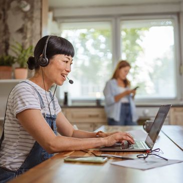 Woman wearing headset working on laptop.