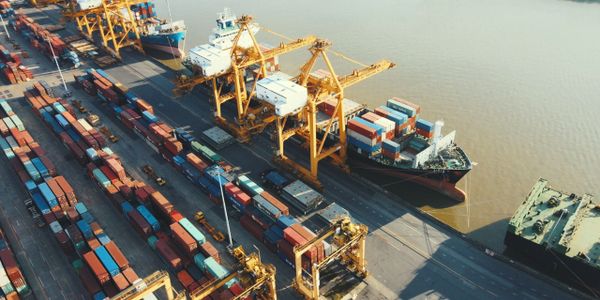 Aerial view of a busy shipping port with cranes and cargo containers.