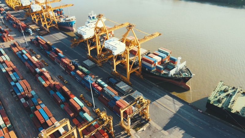 aerial footage of singapore’s busy container port featuring cargo ships, cranes, and loading docks along the waterfront. this video is ideal for illustrating maritime trade, logistics infrastructure, asian shipping routes, and global freight transportation.