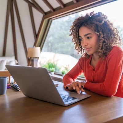 Femme concentrée utilisant un ordinateur portable à la maison.