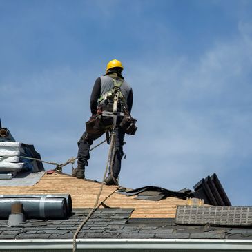 Construction worker in safety gear working on a residential roofing. we specialize in roof inspection and roof replacement.
