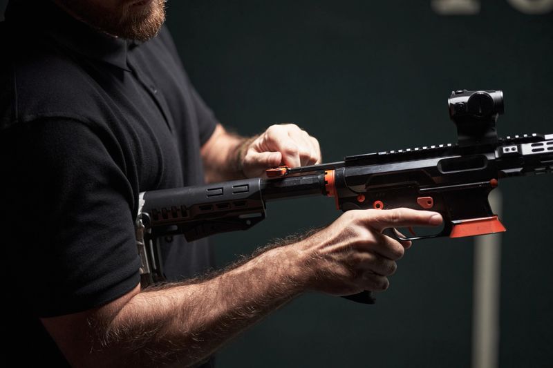 Midsection of anonymous man loading modern rifle at shooting club, focusing on firearm handling and safety, partial view showing strong male arms and tactical weapon