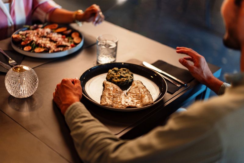A luxurious dining scene featuring elegant plated meals. Two people are enjoying a fine dining experience with beautifully presented dishes in an intimate setting. A focus on gourmet food and ambiance.