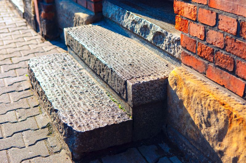 Weathered granite steps, showcasing the intricate patterns and textures of the brick wall. Stone steps, showing the transition from pavement to building