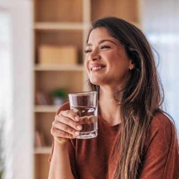 Smiling woman holding a glass of water.