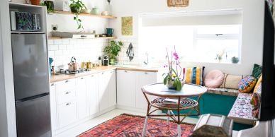Bright kitchen with white cabinets and colorful cushions.