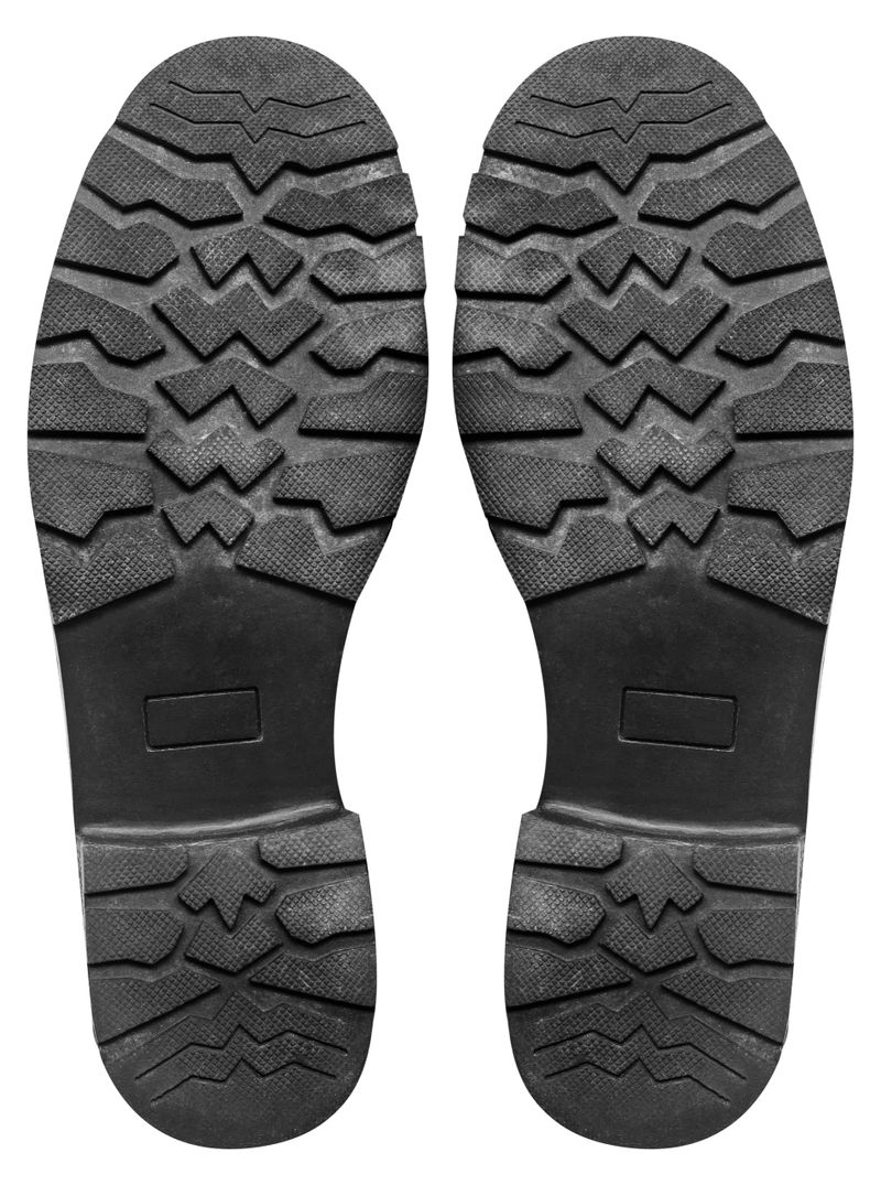Isolated photo of black colored rubber shoe patterned worn protector on white background.