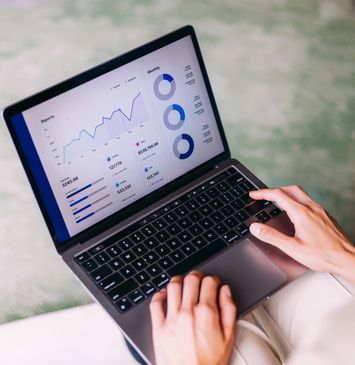 Person analyzing data charts on a laptop screen.