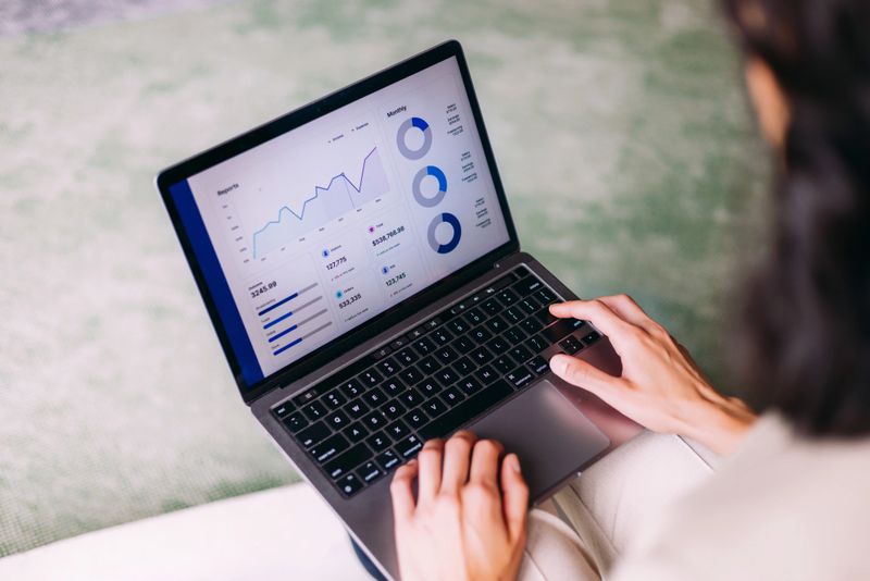 A person working on a laptop computer showing graphs and charts for data insights analysis, embodying productivity, technology, and business planning in a professional setting.
