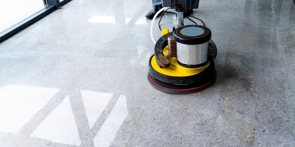 A yellow floor polishing machine buffing a shiny floor.