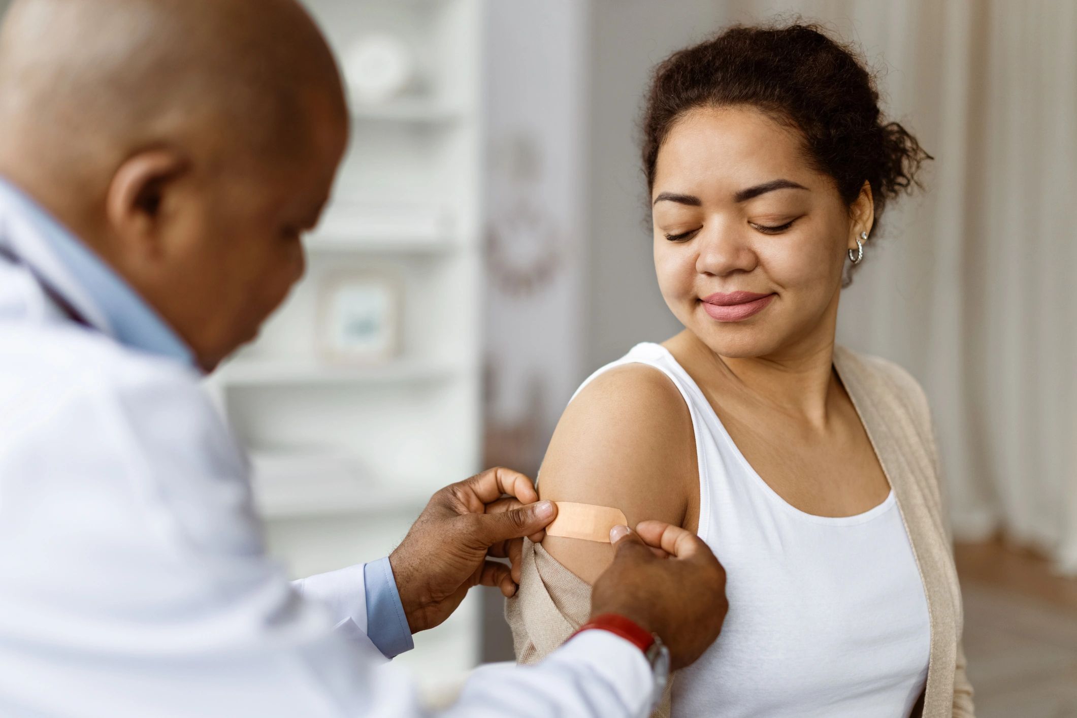 Doctor applying bandage on patient's arm after vaccination.