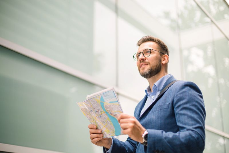 Businessman reading a map in a modern city looking for directions