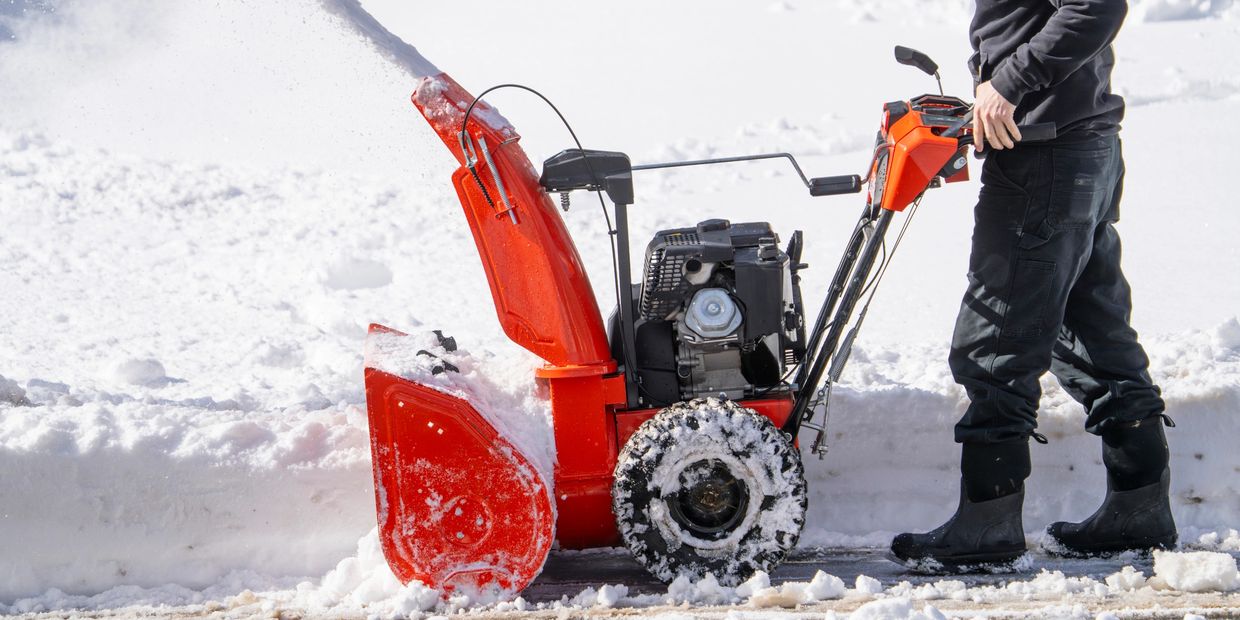 Person using snow blower to clear snow.
