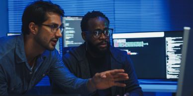 Two men analyzing code on a computer screen.