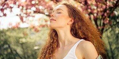 Woman enjoying sunlight with closed eyes outdoors.