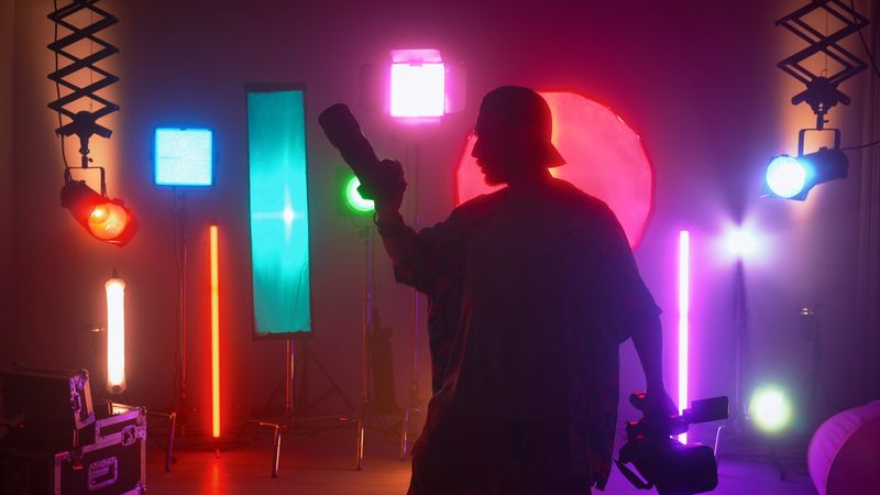 Professional filming pavilion with lighting equipment. The process of preparation for shooting a music video. Operator adjusts the camera behind the backstage.