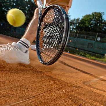 Tennis player hitting ball on clay court.