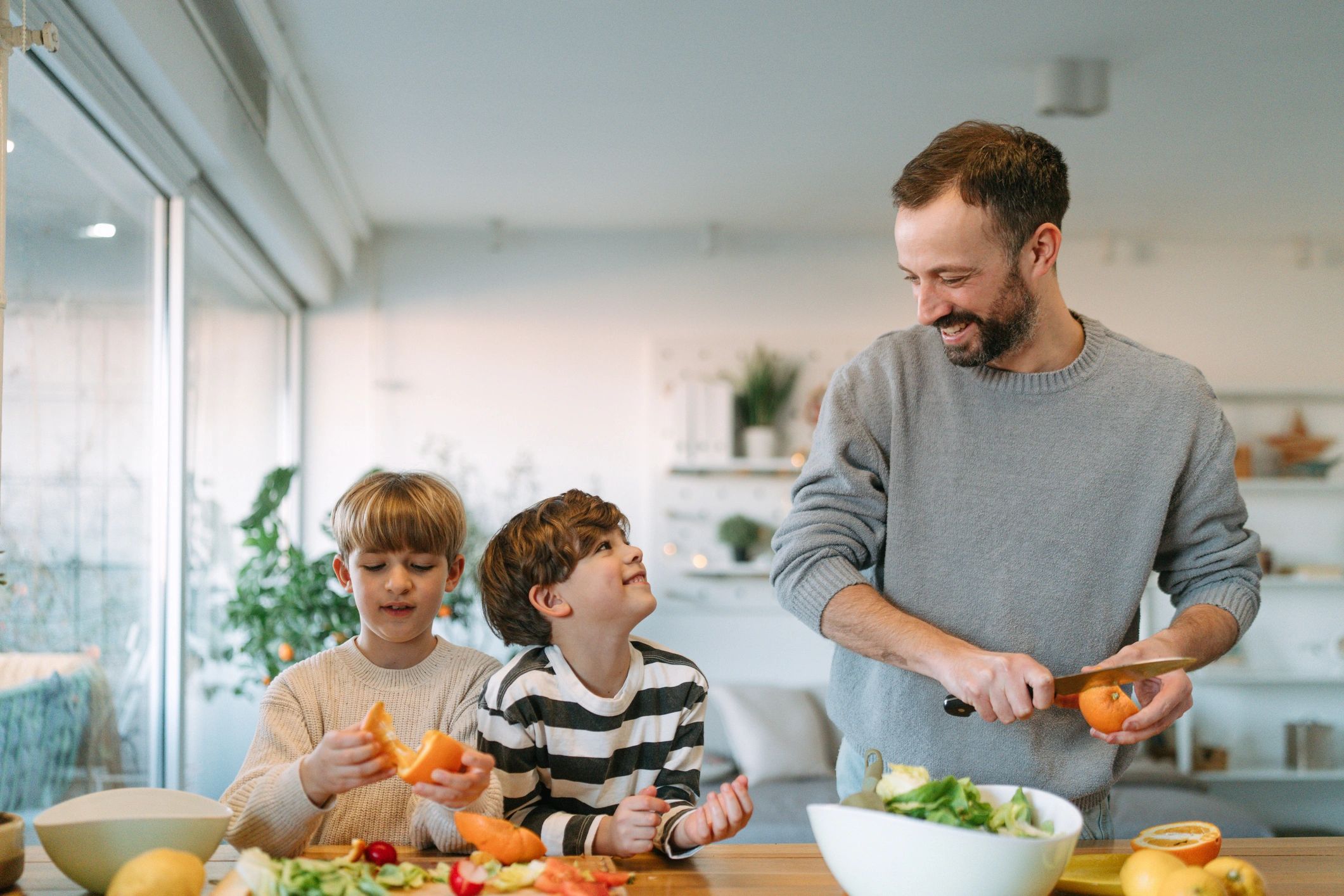 Father and kids preparing food together in a kitchen.