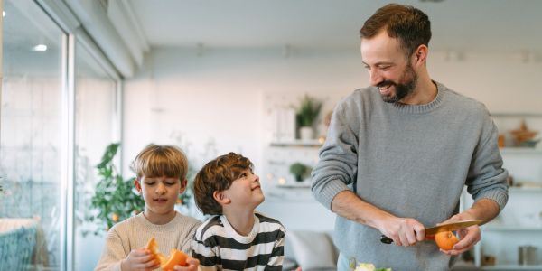 Father preparing food with two children in the kitchen.