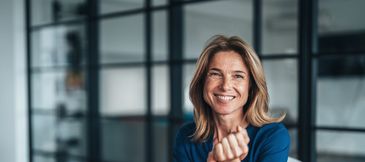 Confident woman smiling with a modern office background.