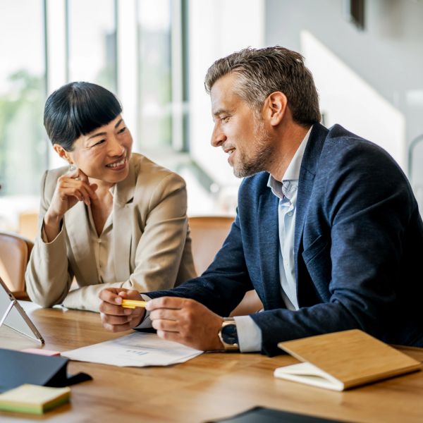 Two colleagues happily discussing work at a desk.