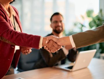 Two professionals shaking hands during a business meeting.