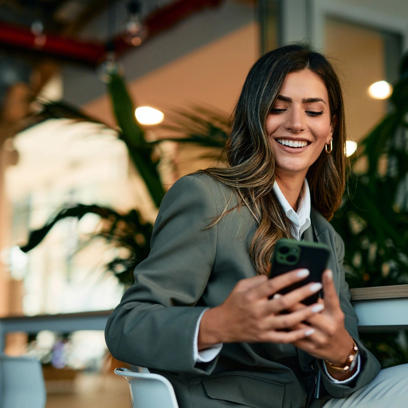 Smiling woman in business attire looking at her phone.
