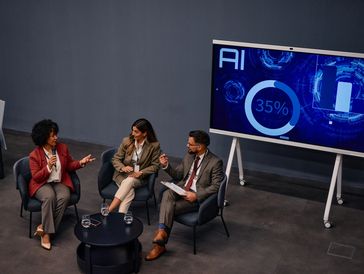 Three professionals discussing AI with a presentation screen.