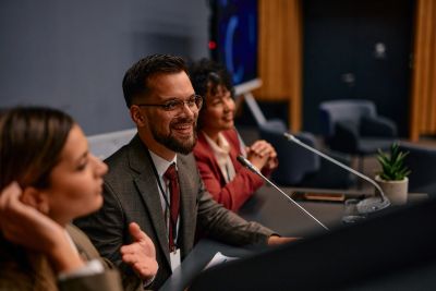 Three professionals engaged in a panel discussion, smiling and speaking into microphones.