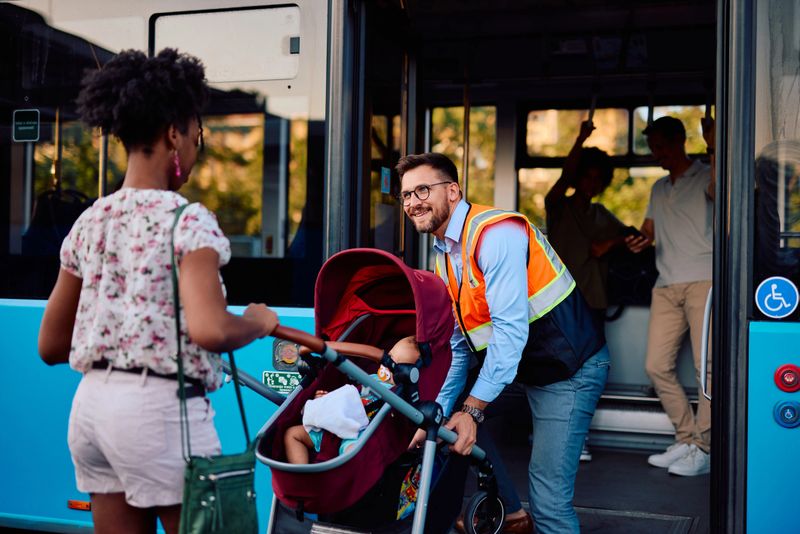 Smiling bus driver helping a young mother boarding a modern city bus with a baby stroller, providing assistance and ensuring a smooth journey for passengers with children