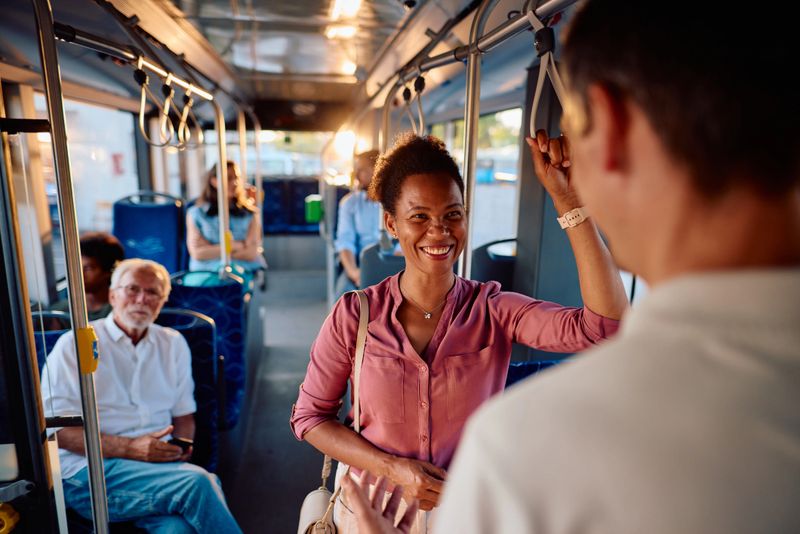 Cheerful African American woman engaging in lively conversation with a friend while commuting on public transport, sharing smiles and enjoying the vibrant city life around them