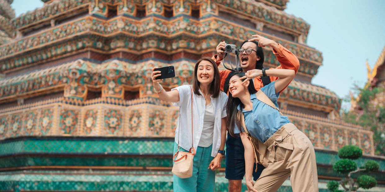 Group of friends taking a selfie in front of a temple in Asia