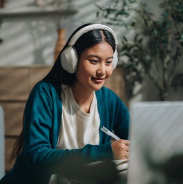 A woman in business attire smiling and shaking hands during a meeting.