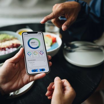 Person showing a smartphone with a calorie tracking app to another person.