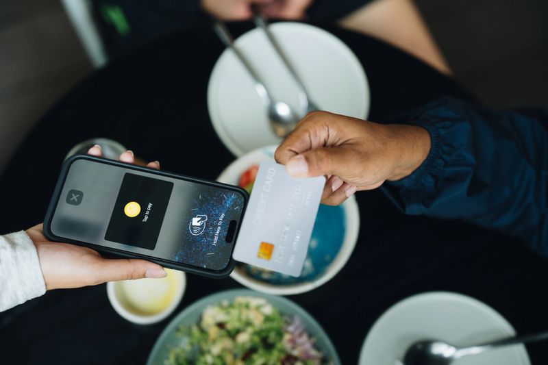 Close-up shot of man tapping a credit card on a smartphone