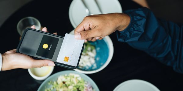 Person paying with a credit card using a mobile payment terminal at a restaurant.