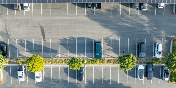 Empty parking lot with few cars and trees.