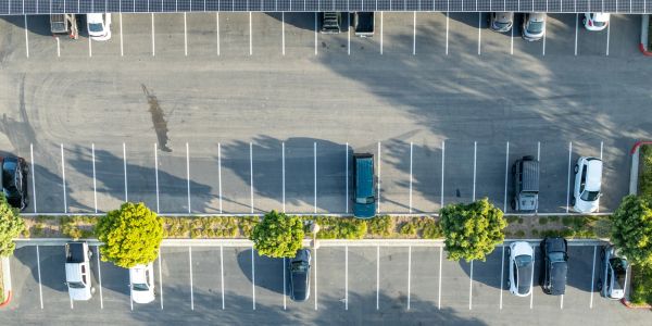 Aerial view of a parking lot with scattered cars and trees.