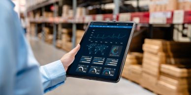 Person holding tablet showing warehouse management analytics in a storage facility.
