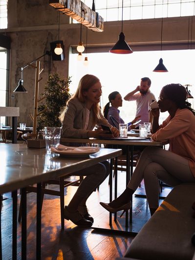 Two women chatting and drinking coffee in a cozy café with natural light.