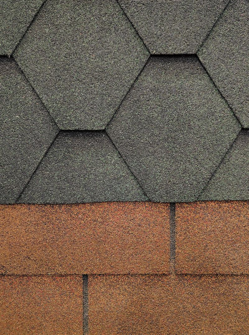 close-up view roofing materials featuring hexagonal gray shingles and rectangular brown shingles, highlighting textures and colors that are used in home construction.