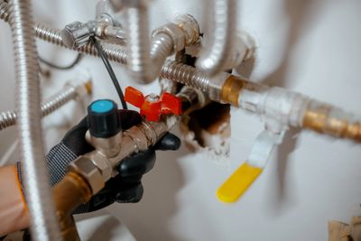 Close-up of plumbing pipes with valves and connectors against a wall.