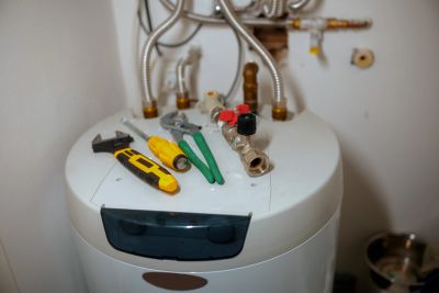 Tools on top of a water heater with connected pipes.
