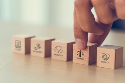 Wooden blocks with ethical values and a finger moving one.