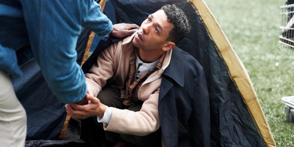 Person inside a tent reaching out to someone outside.
