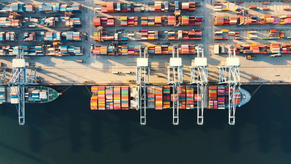 Aerial view of a busy shipping port with colorful containers and cranes.