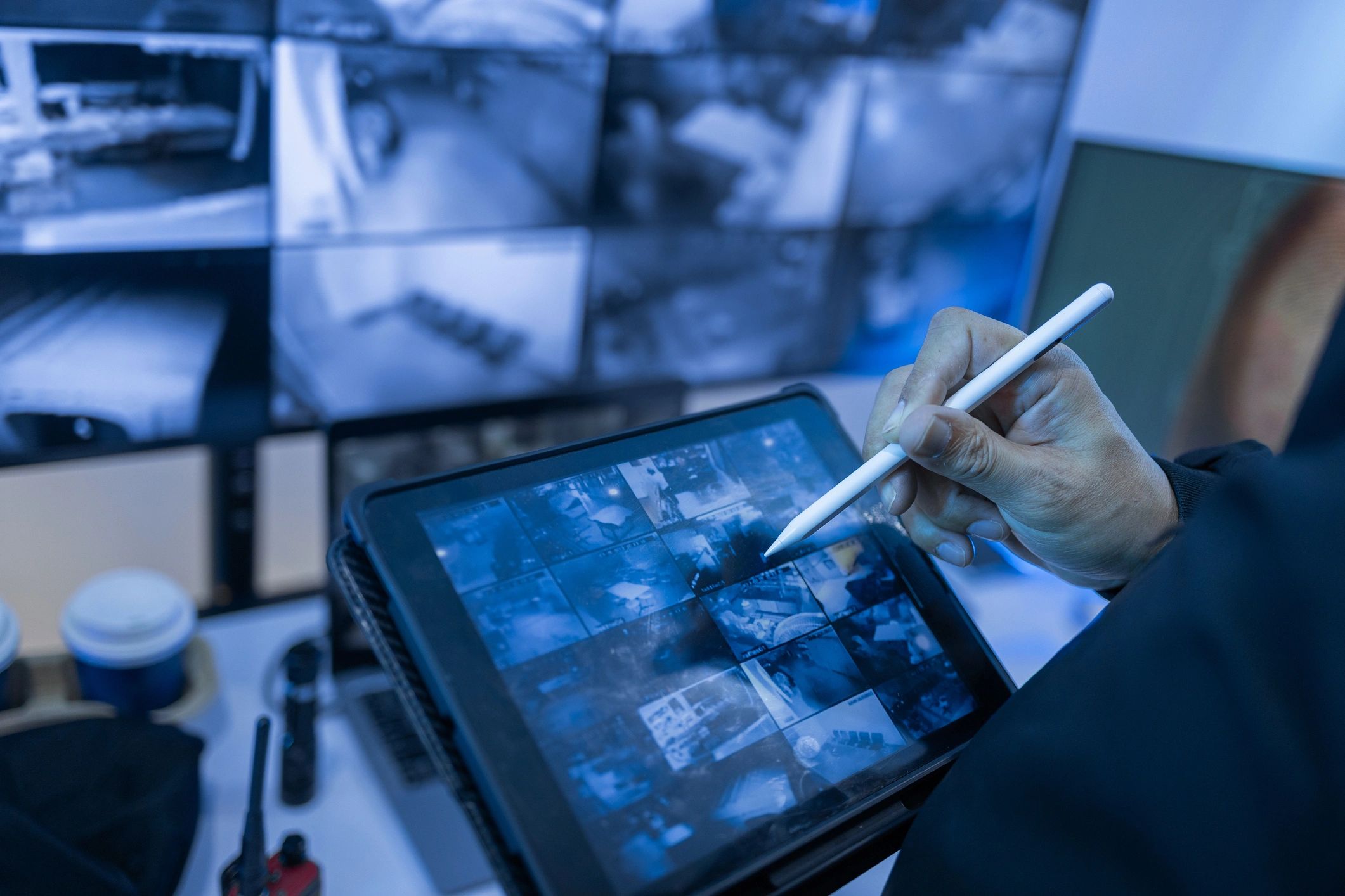 Security professional using tablet to monitor surveillance cameras.