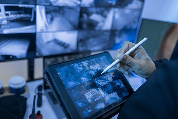 Person analyzing security footage on a touchscreen tablet with a stylus.