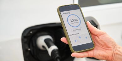 Phone shows 100% charge for electric vehicle.